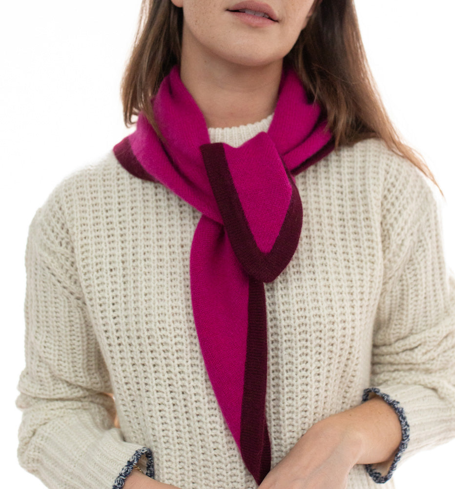 Person wearing a pink and red scarf with a white sweater on a white background