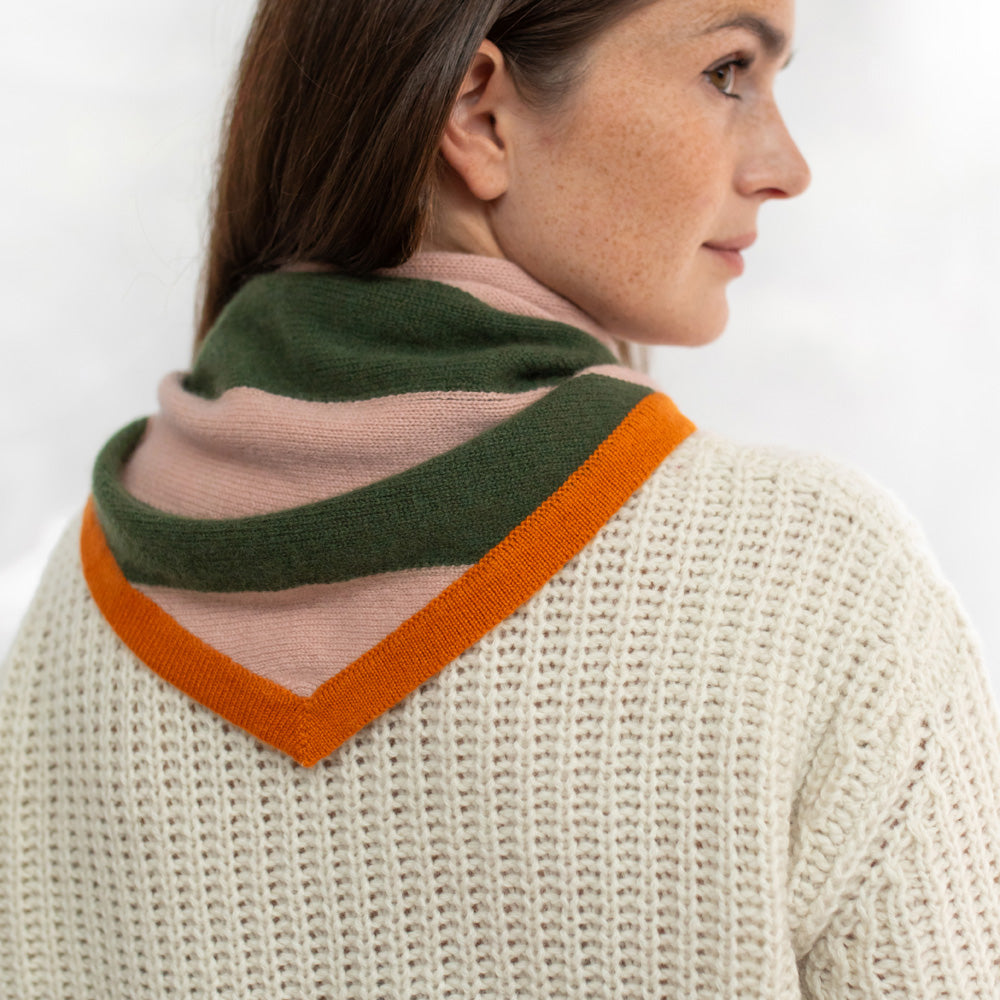 Woman wearing a knitted sweater with a colorful scarf draped over her shoulders against a white background