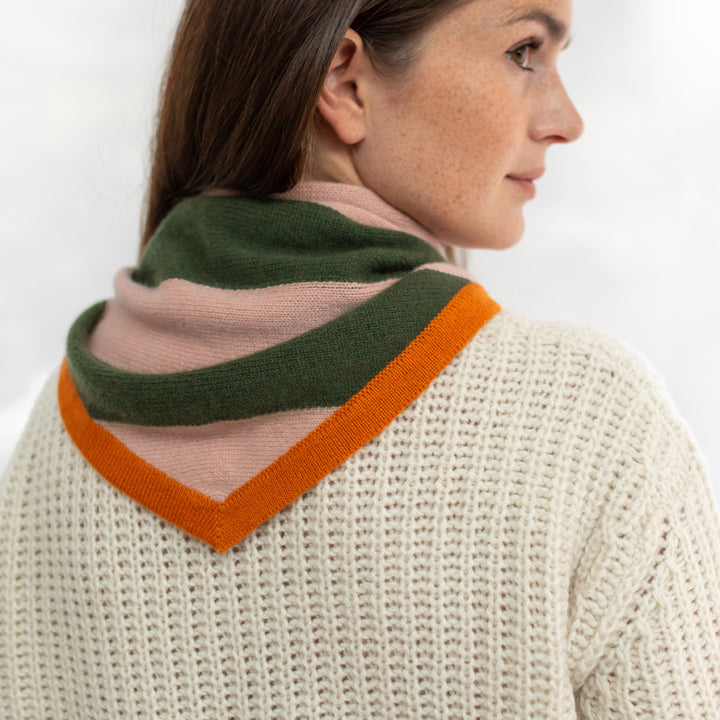 Woman wearing a knitted sweater with a colorful scarf draped over her shoulders against a white background