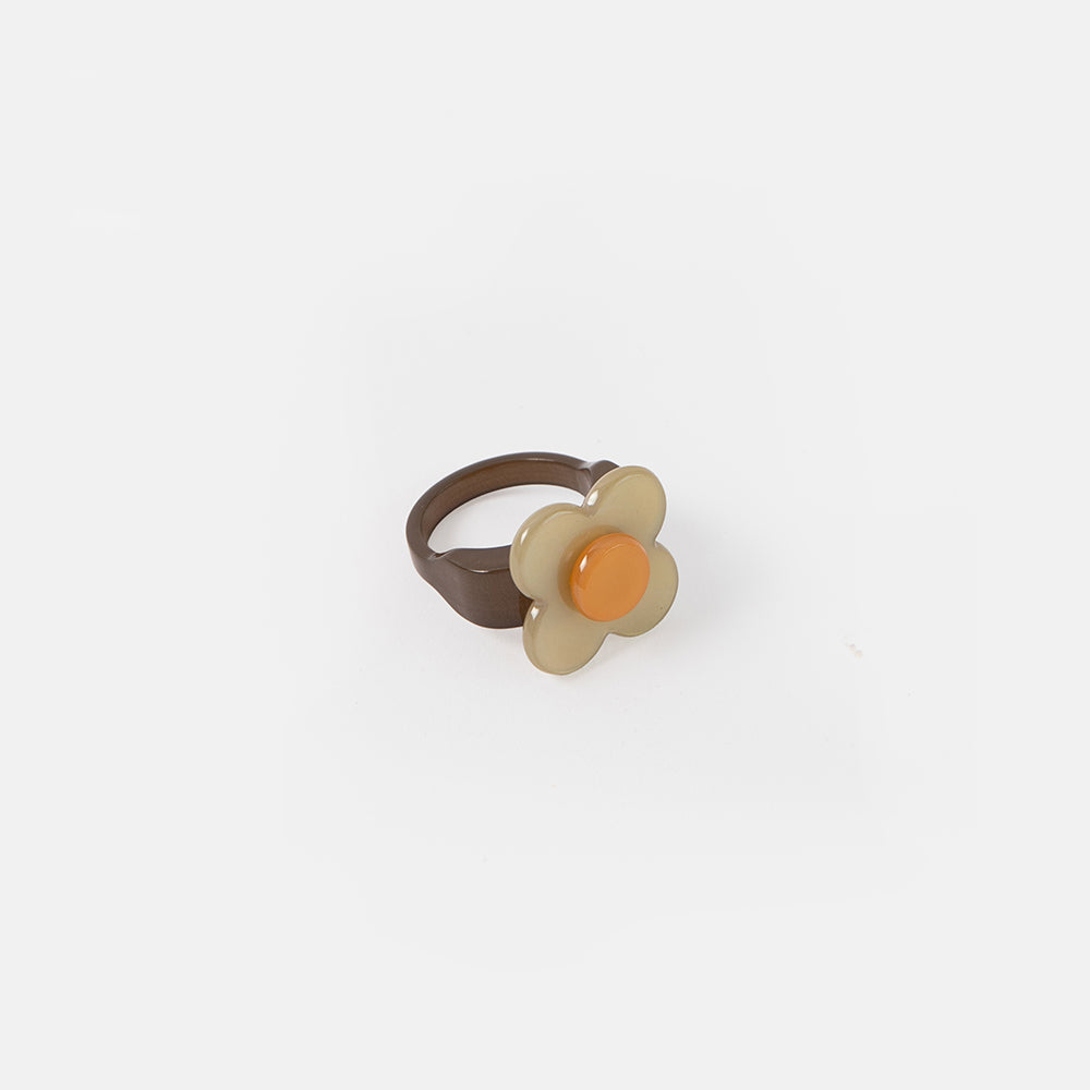 Flower-shaped ring with a brown band and beige center on a white background