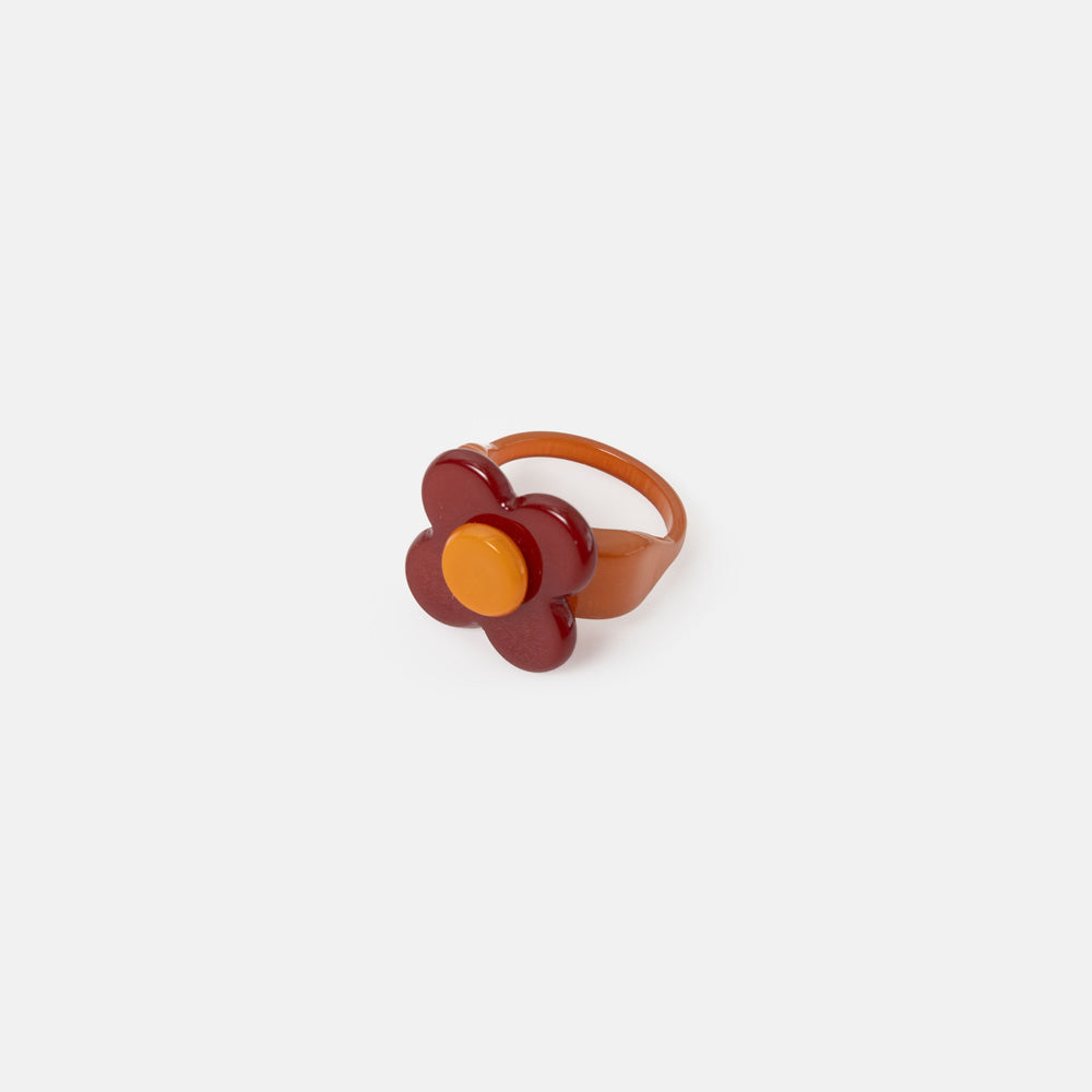 Flower-shaped ring with orange center and brown petals on a white background