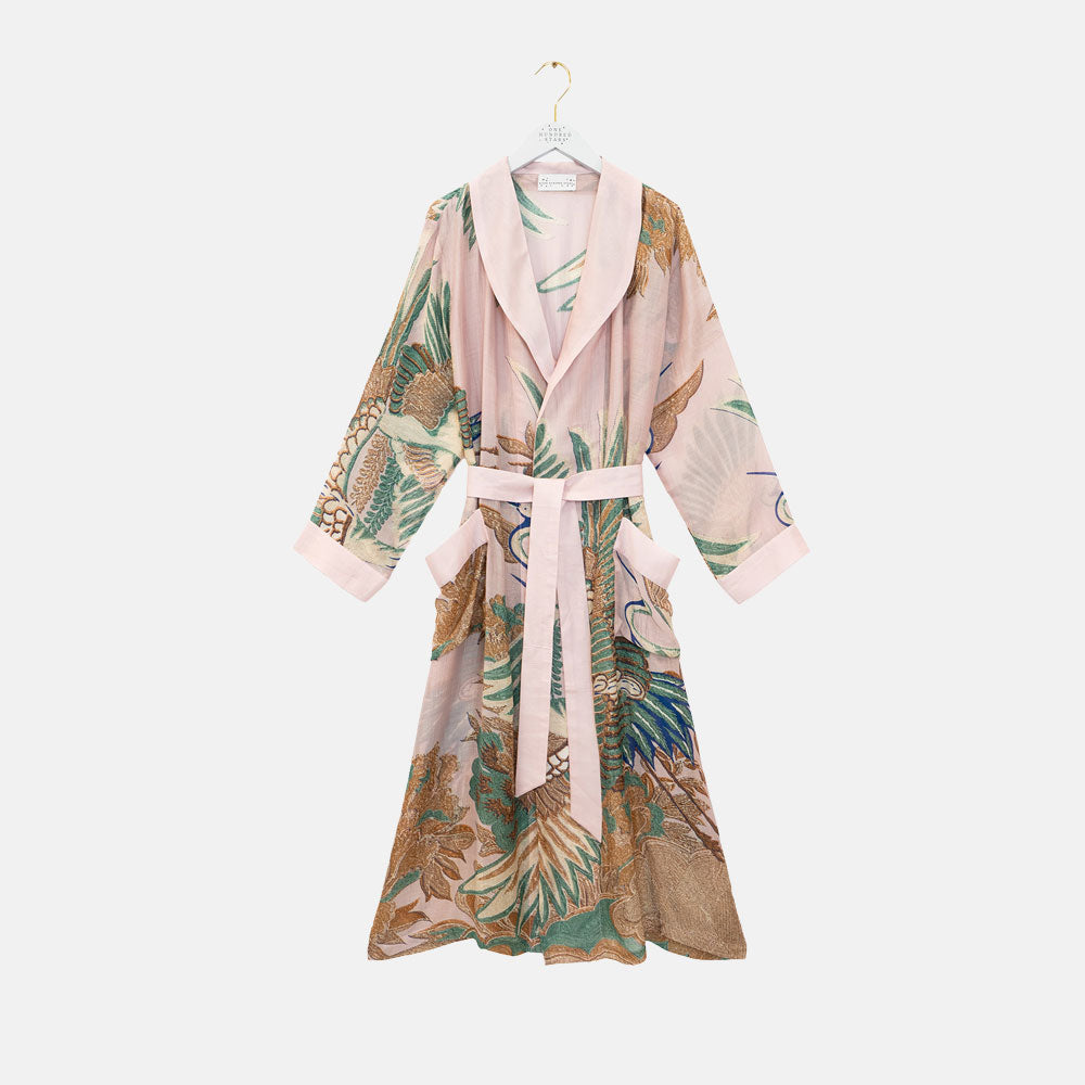 dressing gown featuring design of cranes in green, brown & blue on a light pink background