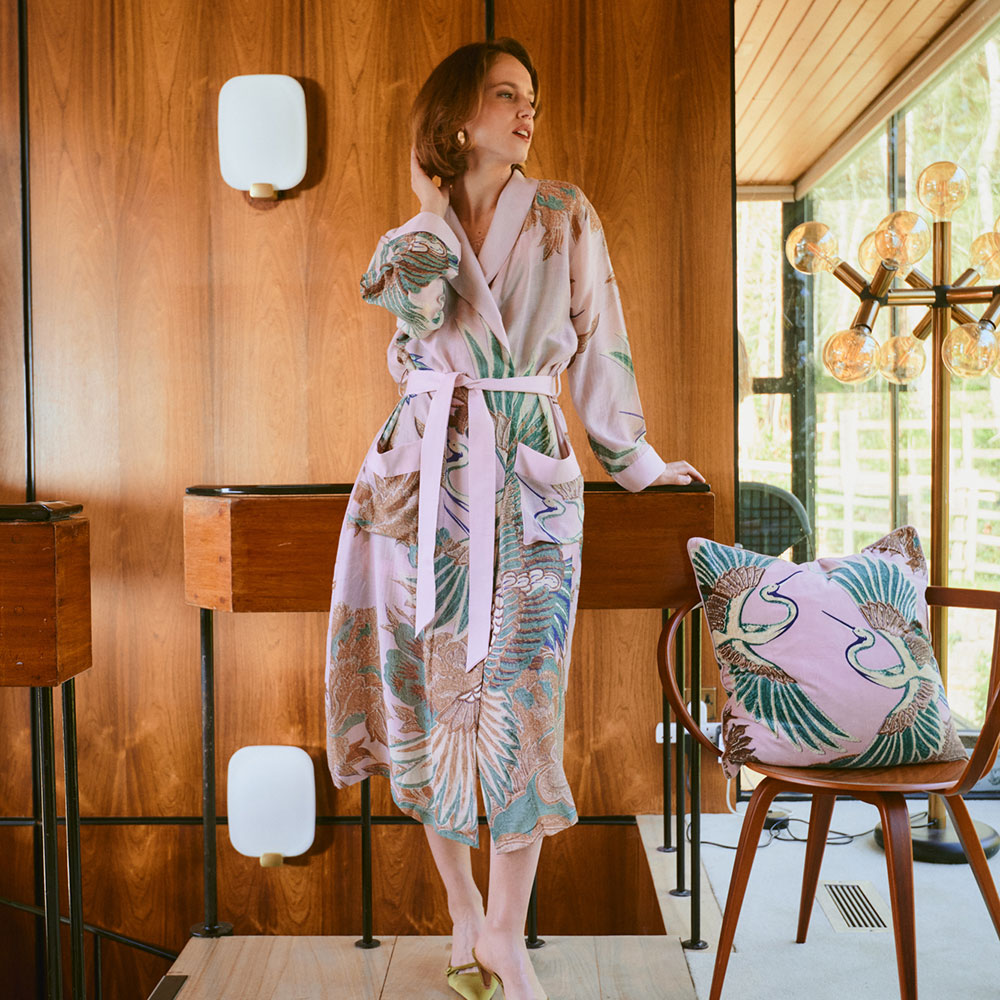 dressing gown featuring design of cranes in green, brown & blue on a light pink background