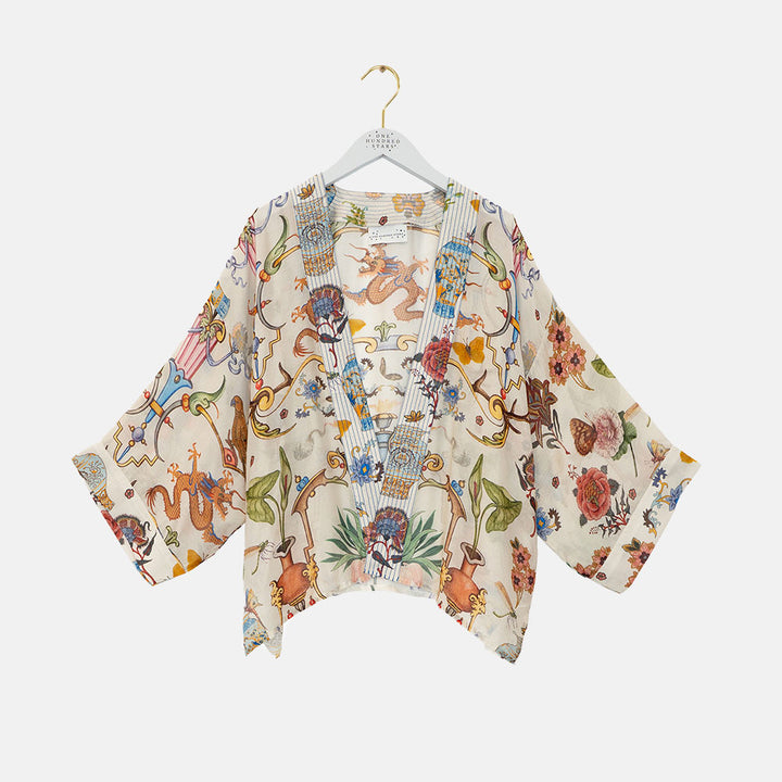 women's short kimono featuring a design of assorted objects, animals & flowers on an ivory base