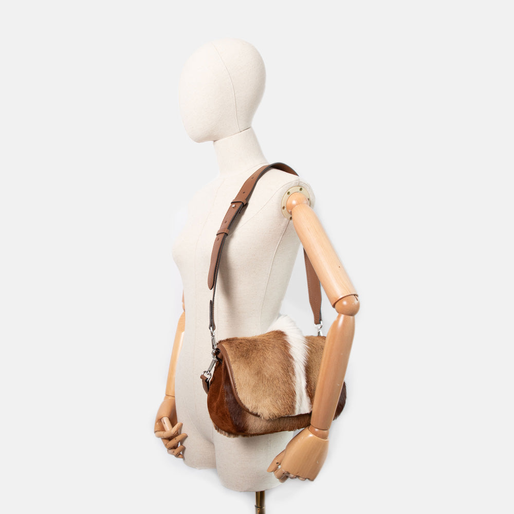 brown & cream springbok leather baguette shaped saddle bag with brown grab handle and crossbody strap