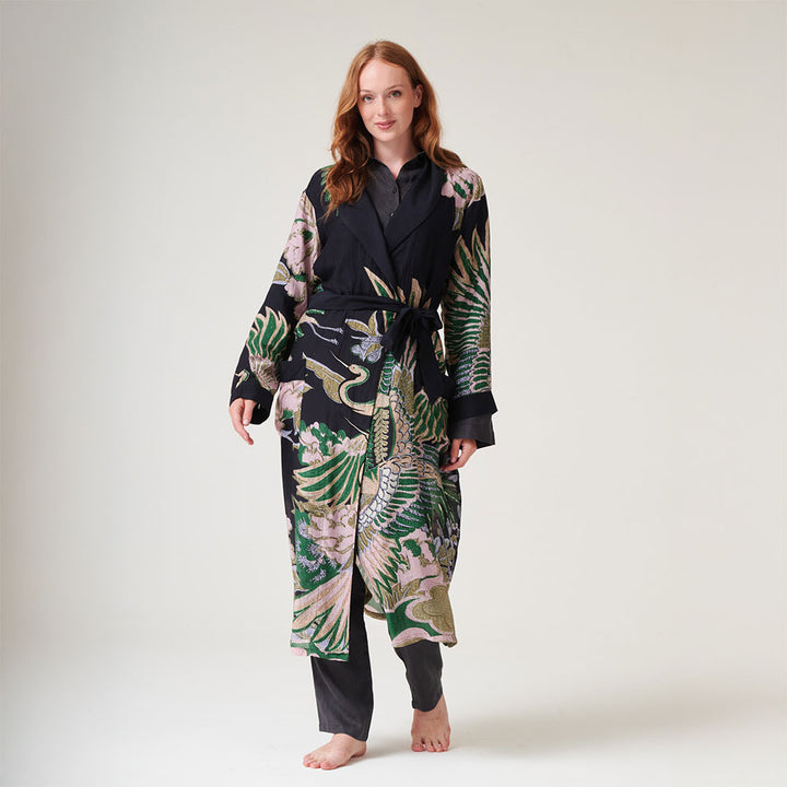 women's dressing gown in black featuring a design of cranes in sand, pink & green, worn with pyjamas