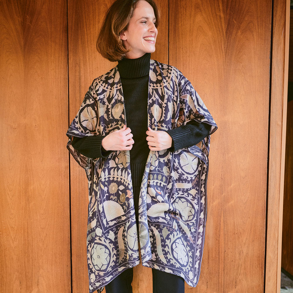 woman wearing a dark grey with beige pattern throwover top over a dark green roll neck jumper