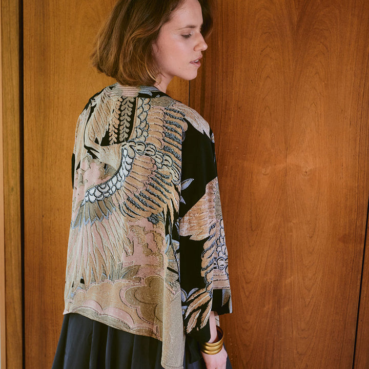 black short kimono jacket with cranes design in sand & light pink, worn with a black dress underneath