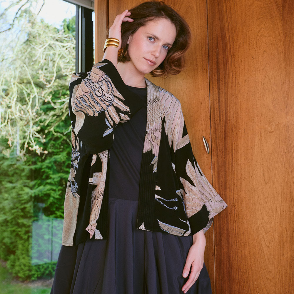 black short kimono jacket with cranes design in sand & light pink, worn with a black dress underneath