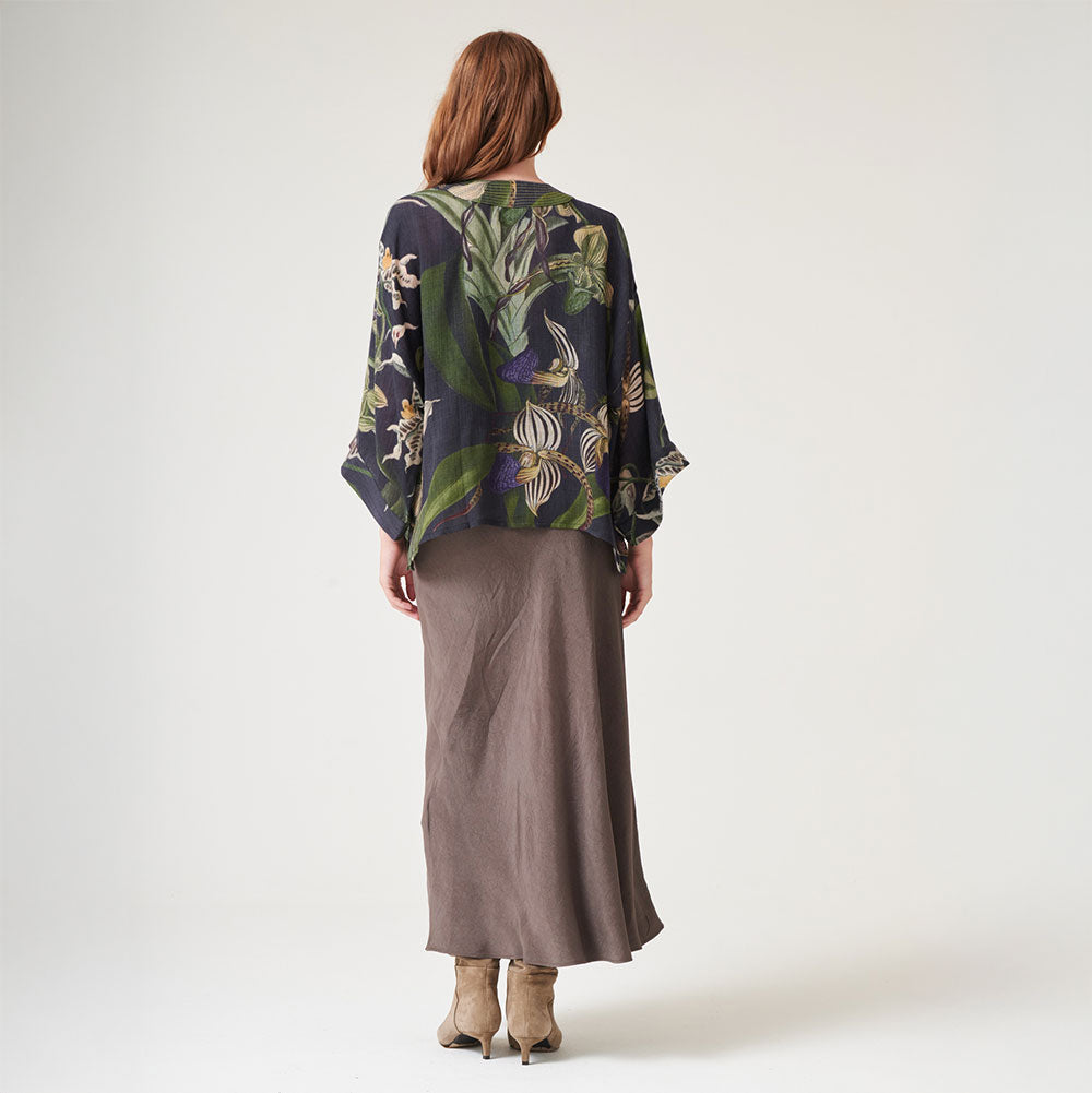 black wool short kimono jacket with orchid print in green and purple, worn with a brown dress and suede boots