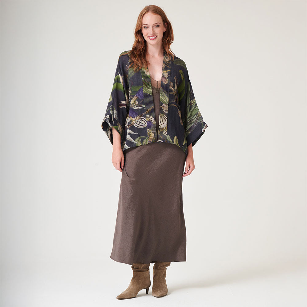 black wool short kimono jacket with orchid print in green and purple, worn with a brown dress and suede boots