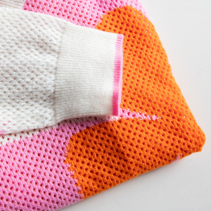 Colorful knitted fabric with pink, orange, and white sections on a light background
