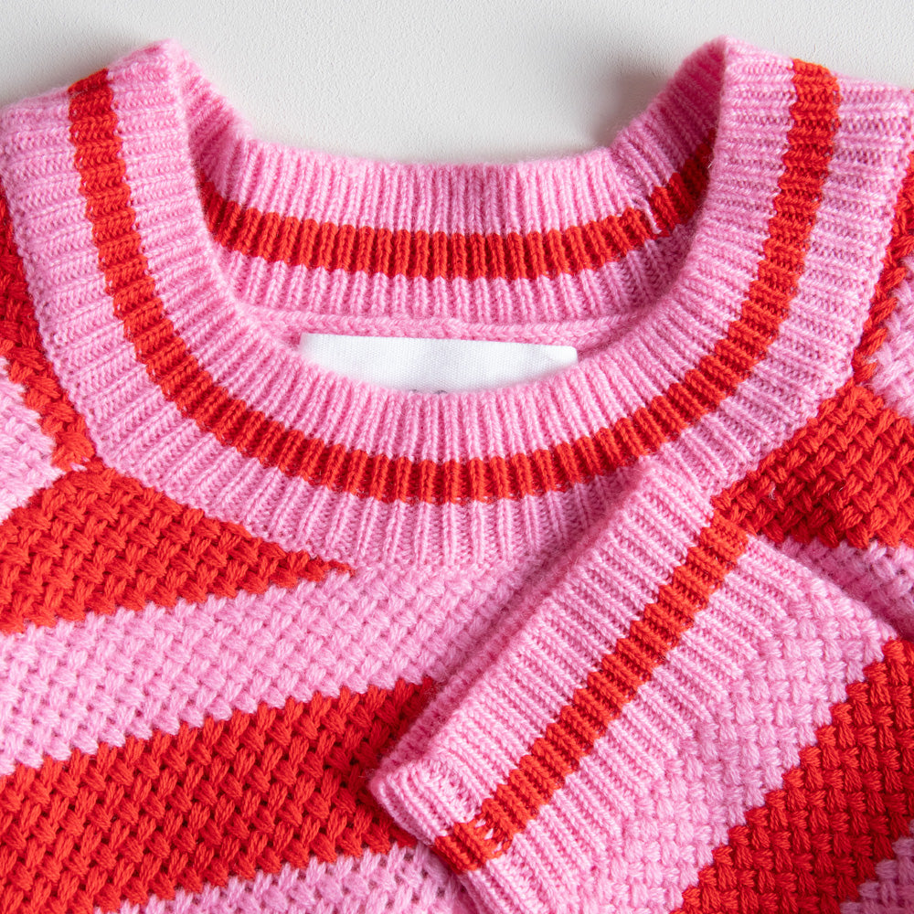 Close-up of a pink and red striped sweater with a white background