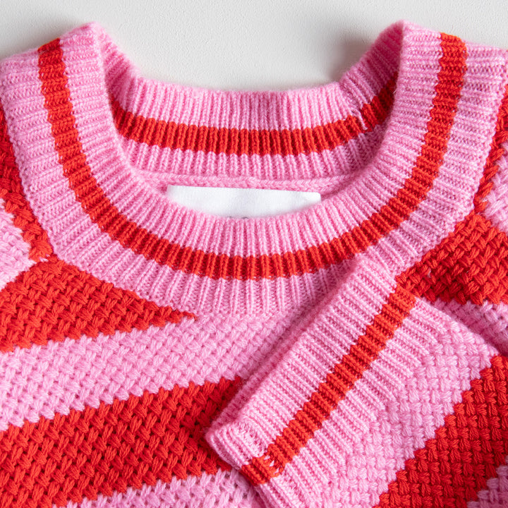 Close-up of a pink and red striped sweater with a white background