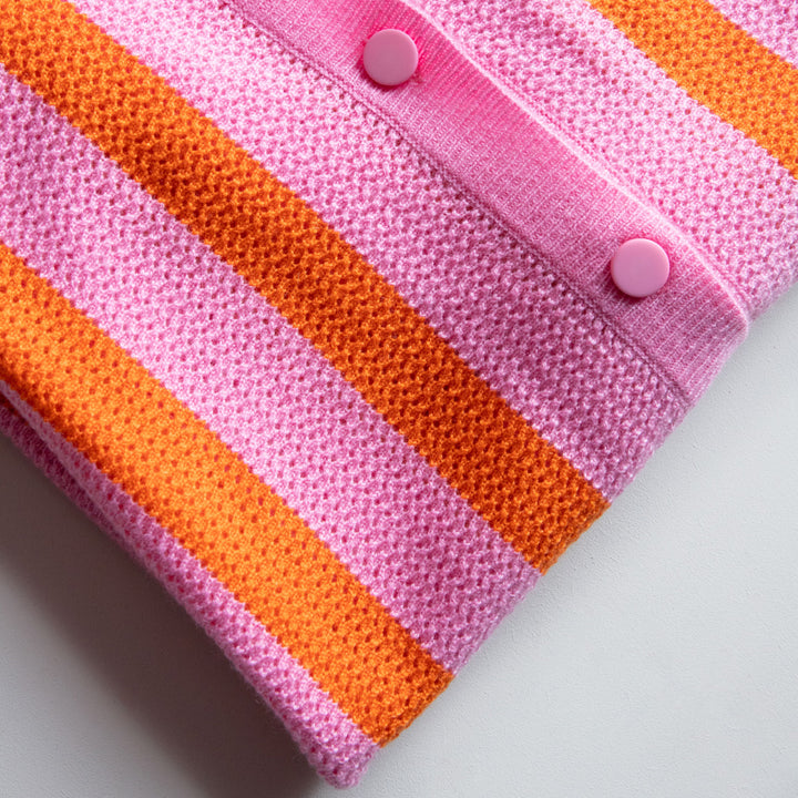 Close-up of a pink and orange striped knitted shirt with buttons on a light grey background
