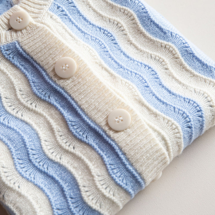 Close-up of a knitted knitted vest with wavy pattern and buttons on a light background