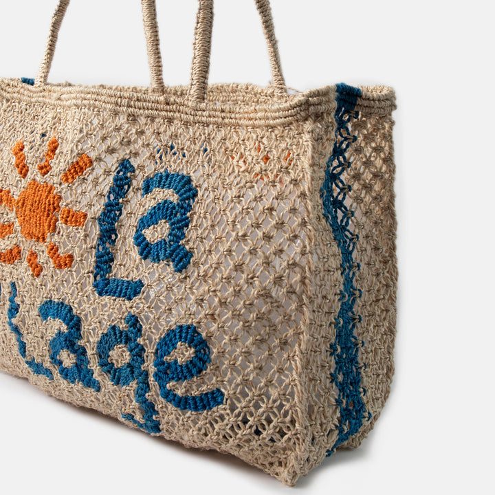 Jute bag with embroidered 'la plage' text and sun design on a white background