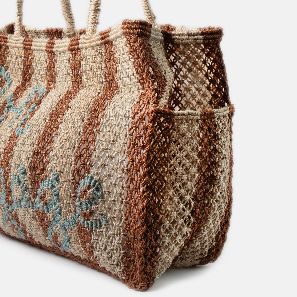 brown & natural stripe jute shopper with the words bon voyage in light blue, against a white background