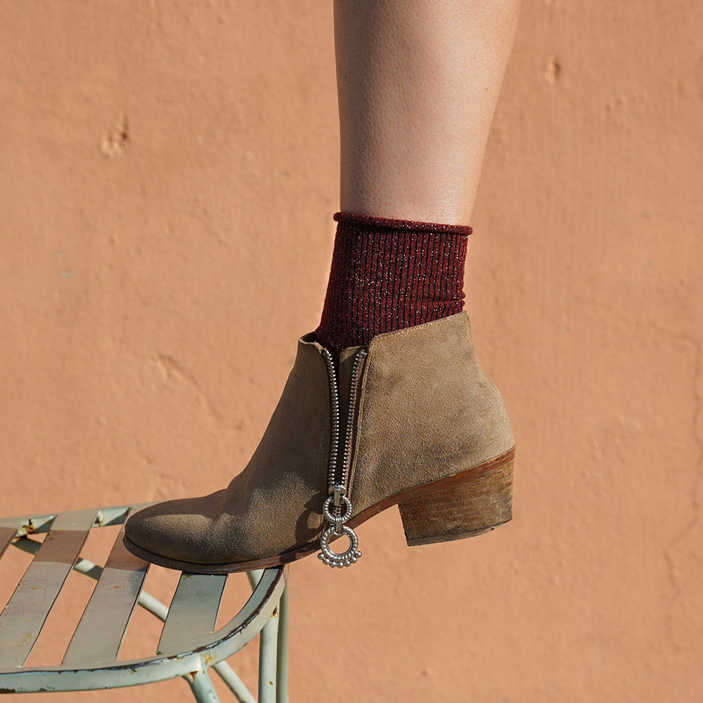 person wearing burgundy sparkly socks win a tan brown suede ankle boot