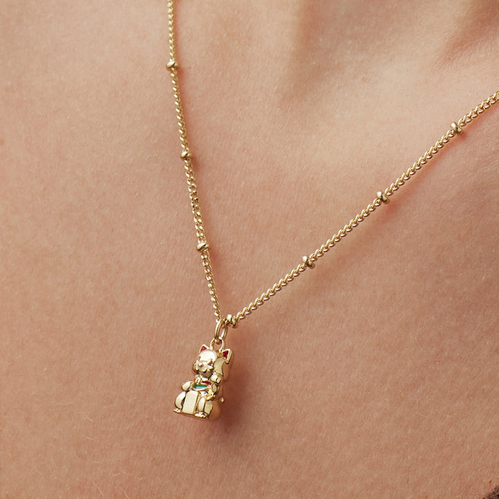 Woman wearing a gold necklace with a cat-shaped pendant