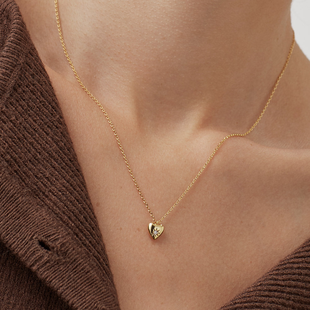 woman wearing gold necklace with gold heart charm set with star shaped cubic zirconia
