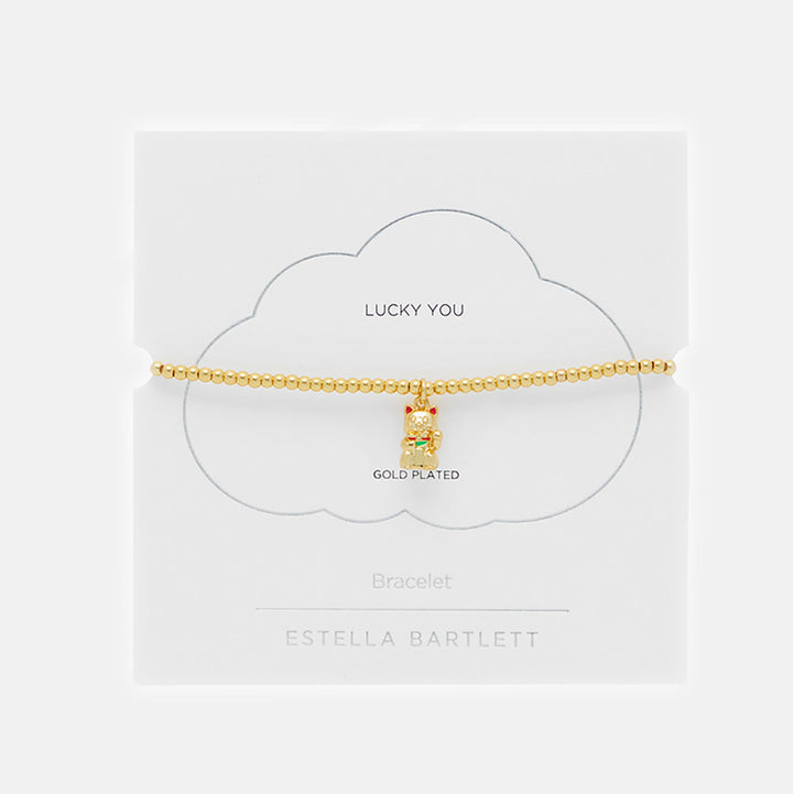 Gold beaded bracelet with a waving lucky cat charm in packaging on a white background