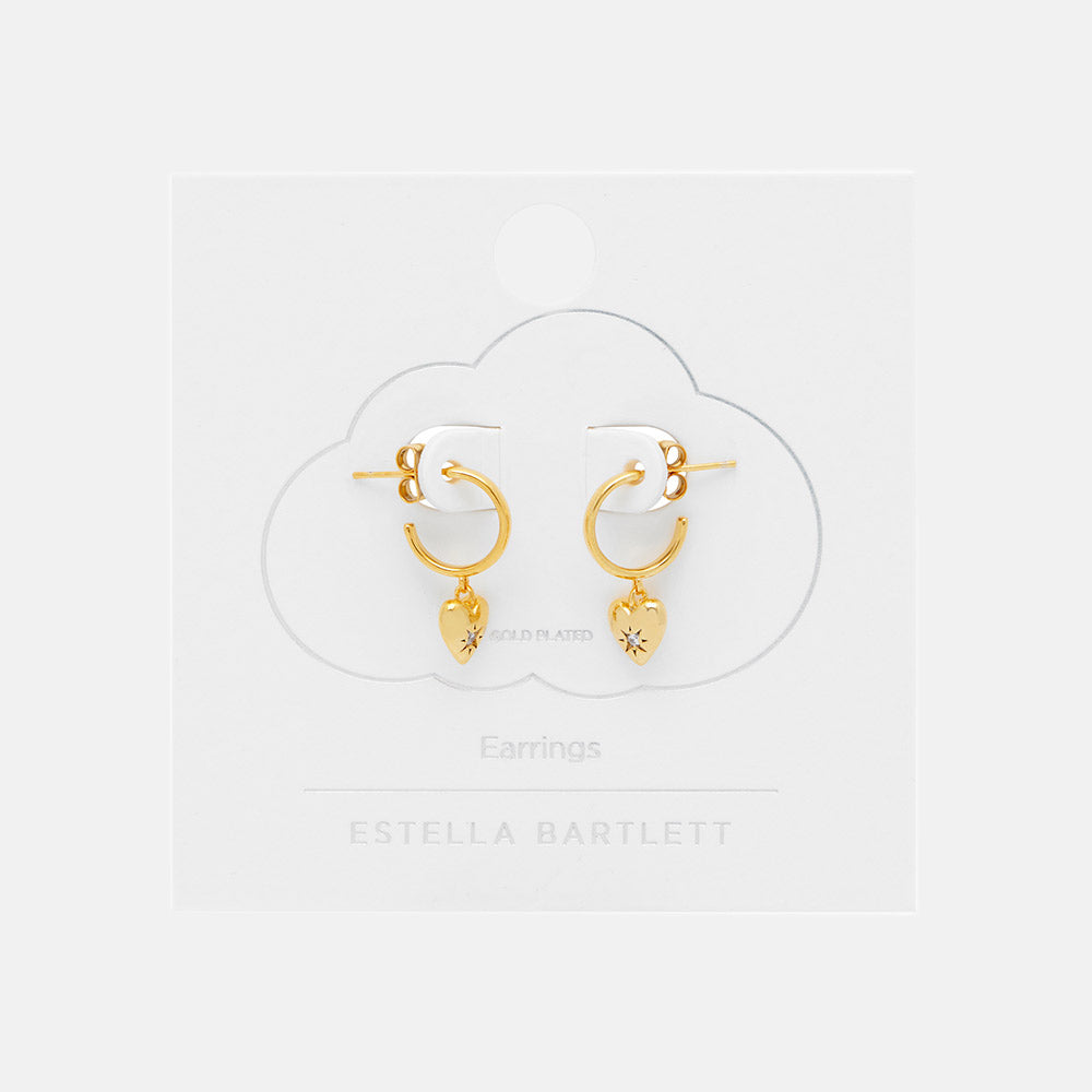 Gold hoop earrings with heart charms on a white background, branded 'Estella Bartlett'.