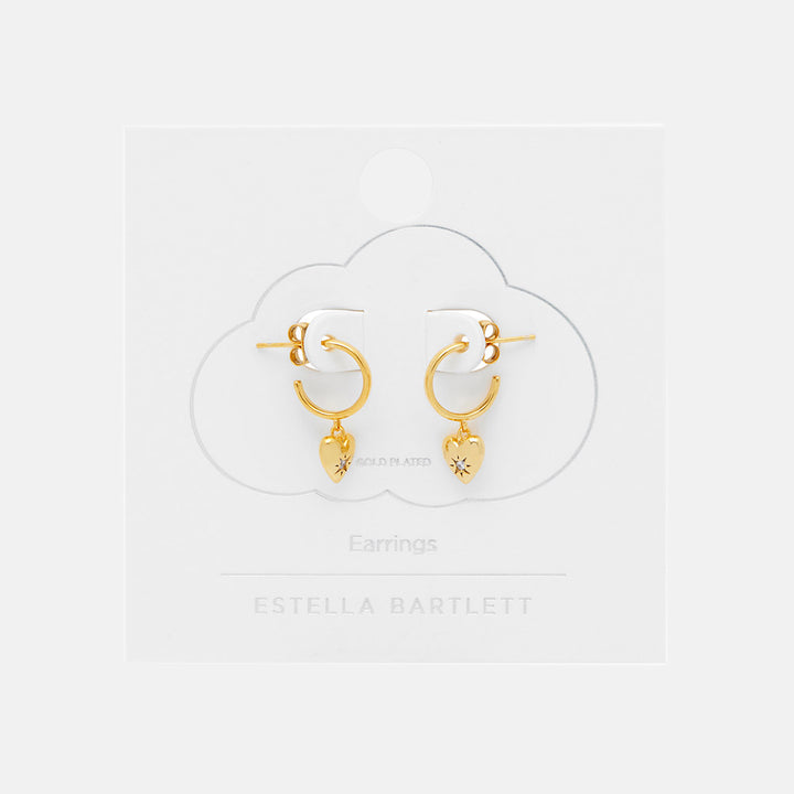 Gold hoop earrings with heart charms on a white background, branded 'Estella Bartlett'.