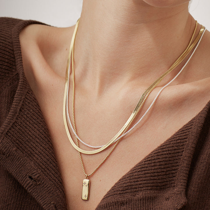 woman wearing a double chain necklace with larger flat gold chain and smaller silver chain
