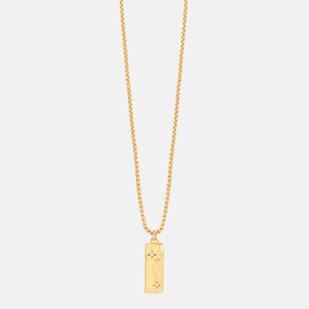 Gold necklace with a rectangular pendant set with cubic zirconia stars on a light grey background