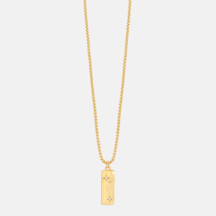 Gold necklace with a rectangular pendant set with cubic zirconia stars on a light grey background