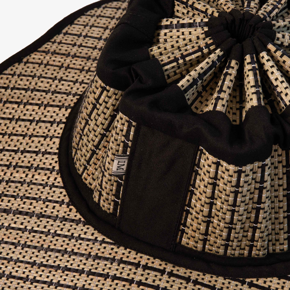 Black and beige woven hat with a knot on a matching background