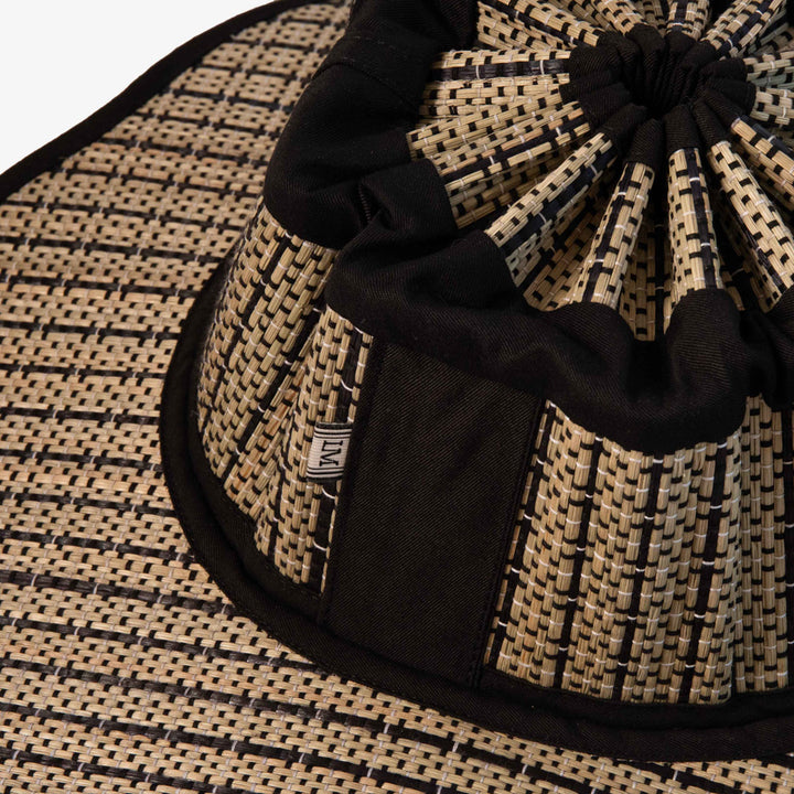 Black and beige woven hat with a knot on a matching background