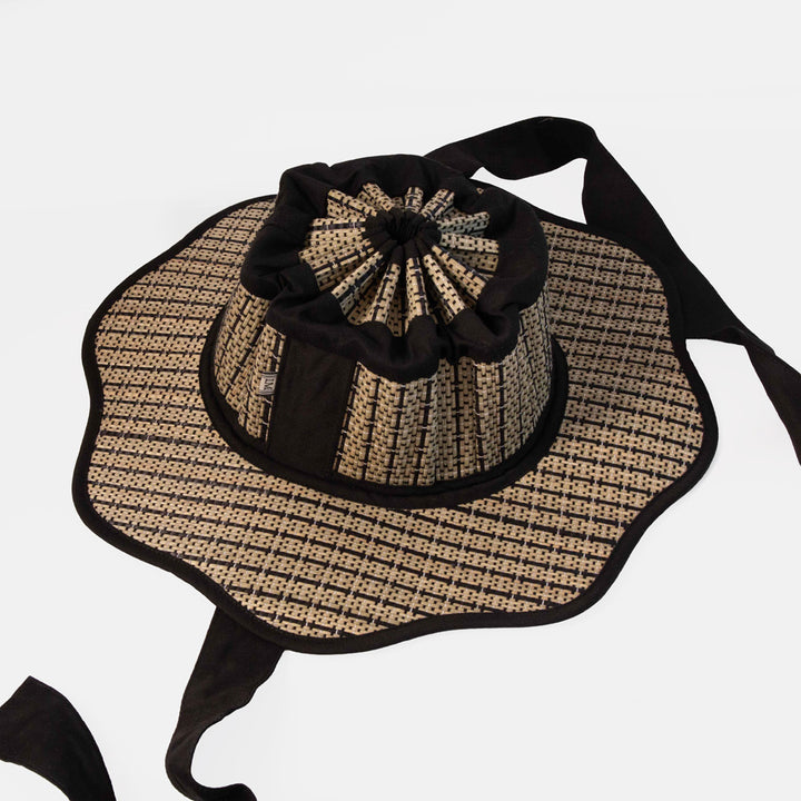 Woven sun hat with black trim on a white background