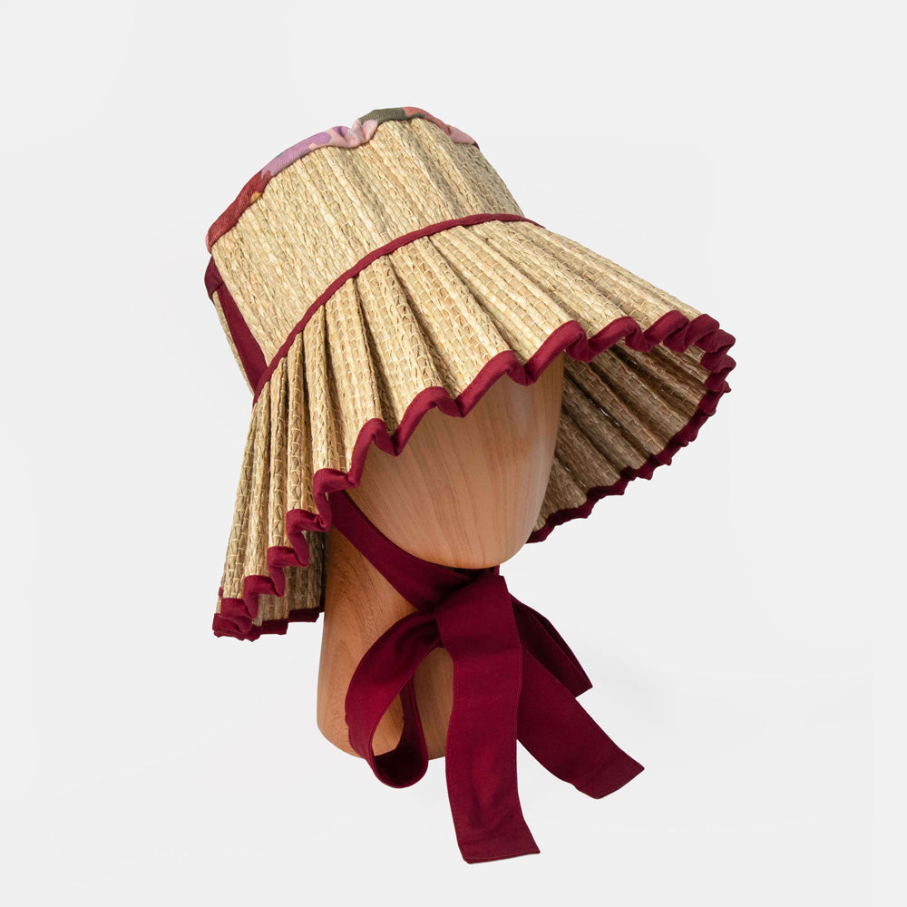 Straw hat with red trim on a mannequin head against a white background