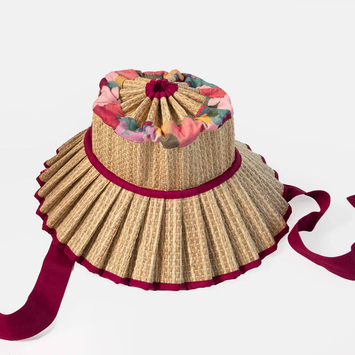 Woven hat with floral top and red band on a white background
