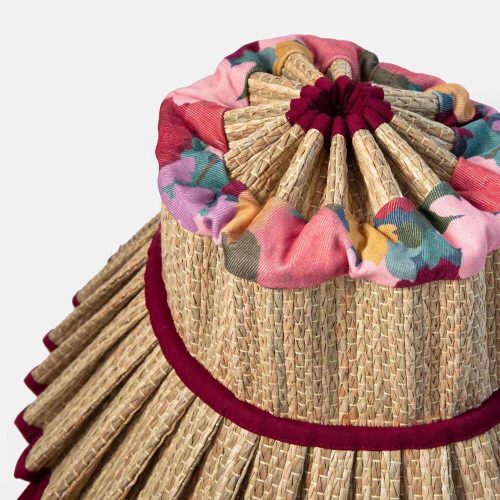 Woven straw hat with colorful fabric trim on a white background