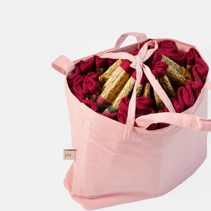Woven straw hat with colorful fabric trim collapsed and packed in a pink bag