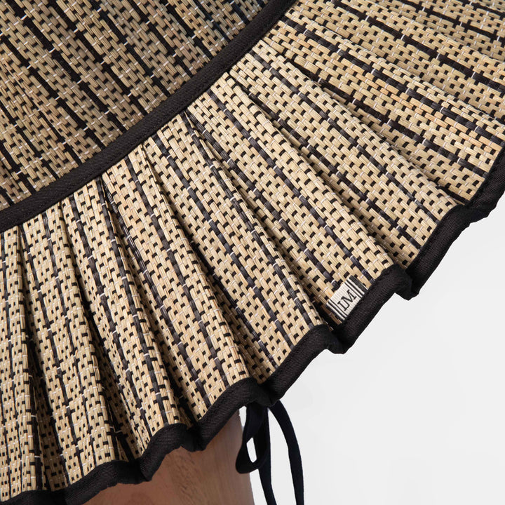 Close-up of a woven sun hat with black and beige pattern on a white background