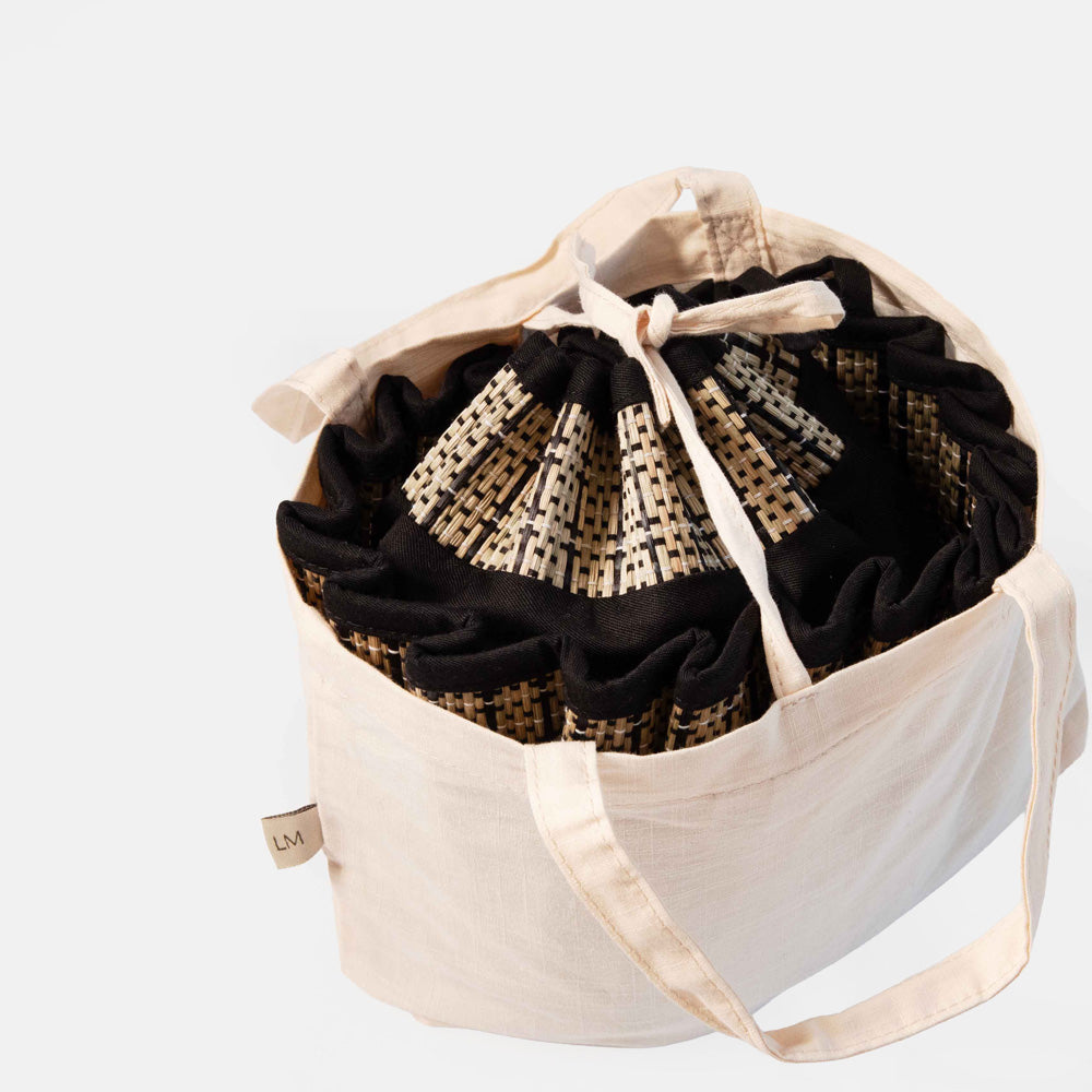 White drawstring bag with black and beige collapsible straw hat on a white background