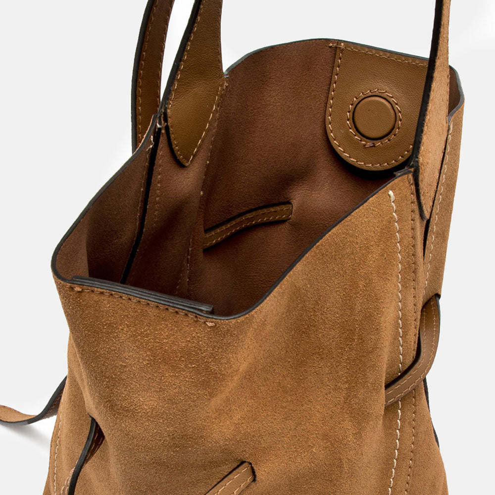 Brown suede handbag with a strap on a light grey background