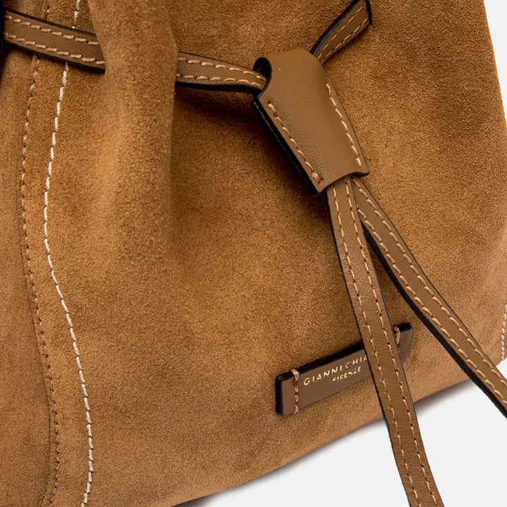 Brown suede handbag with a strap on a light grey background