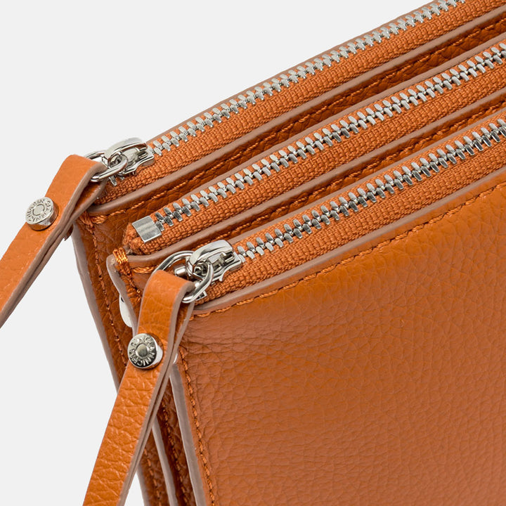 orange leather crossbody bag on a light grey background