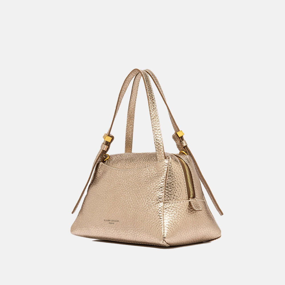 Gold handbag with matching strap on a light beige background