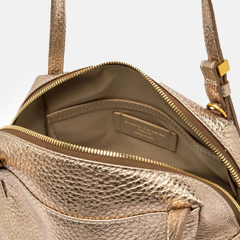 Gold handbag with matching strap on a light beige background