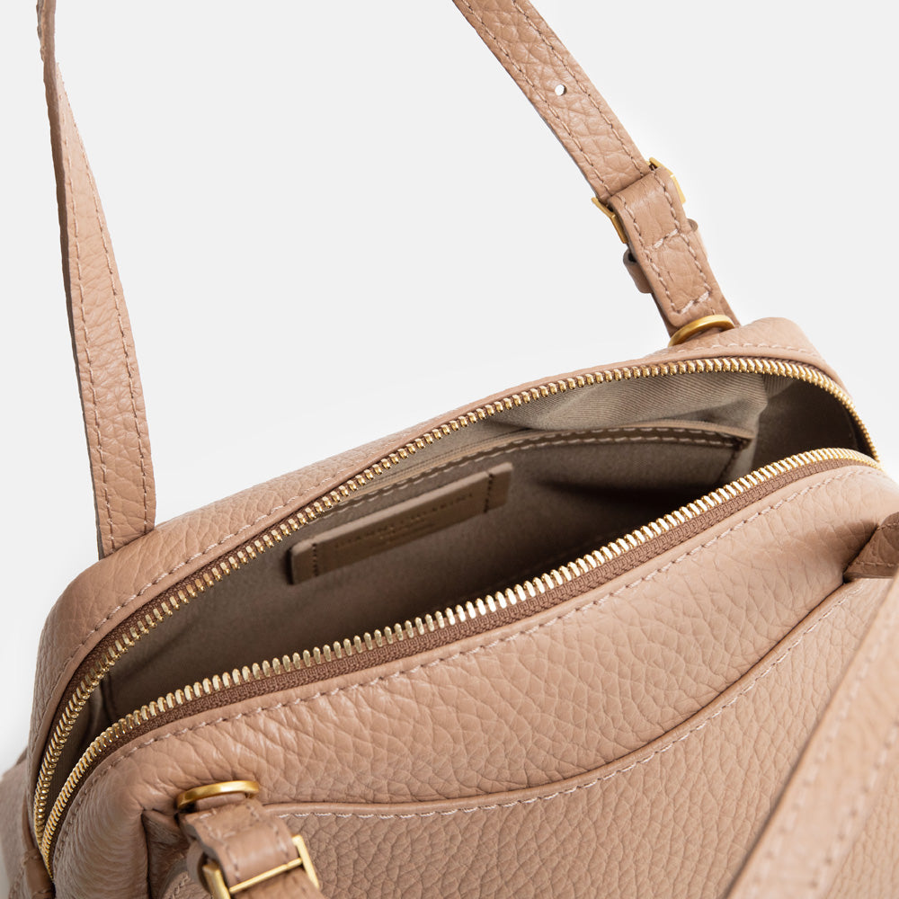 brown leather handbag with canvas internal lining on a light grey background