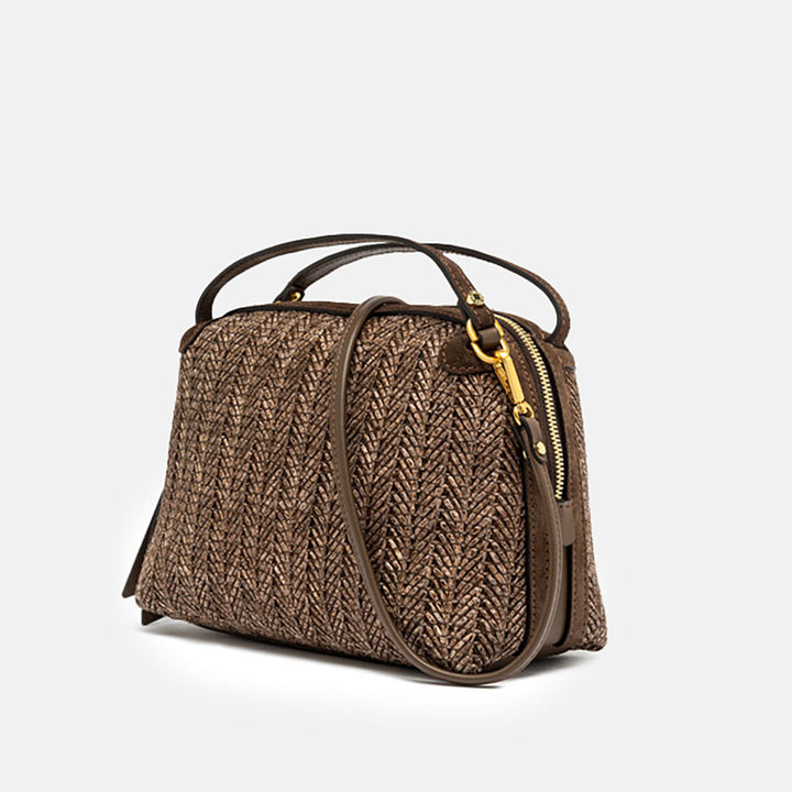 Dark brown woven straw handbag with a strap on a light grey background