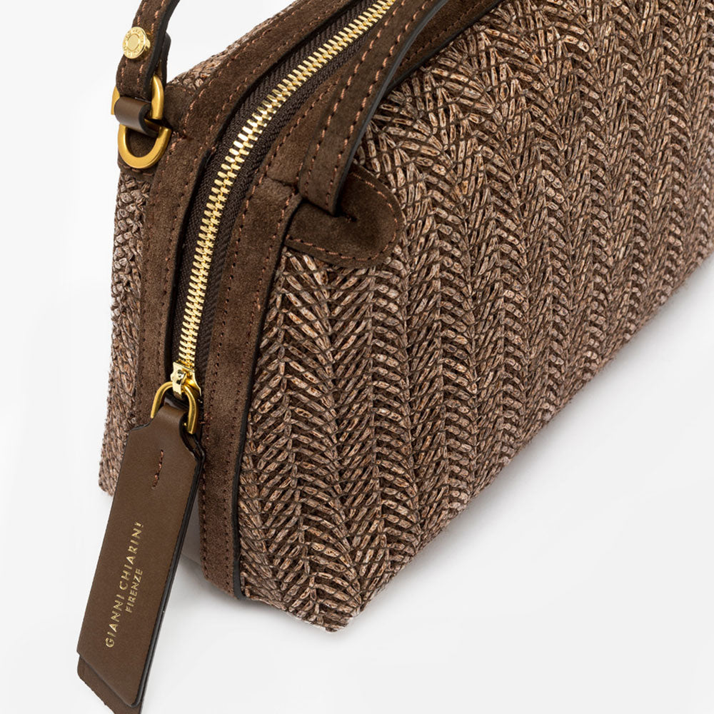 Dark brown woven straw handbag with a strap on a light grey background