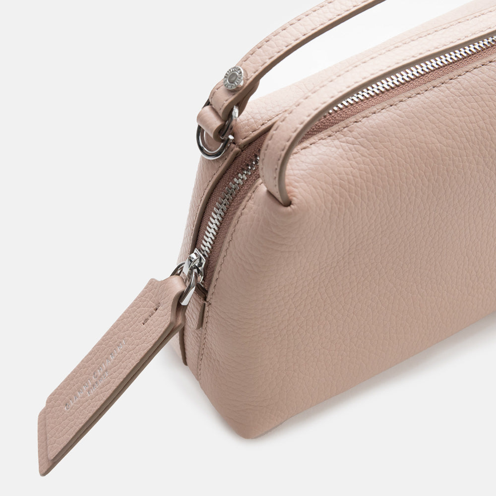 light pink leather handbag with a silver zip on a light grey background