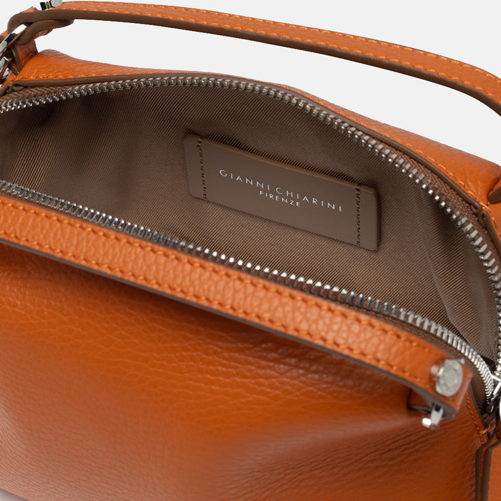 orange leather handbag with canvas internal lining on a light grey background